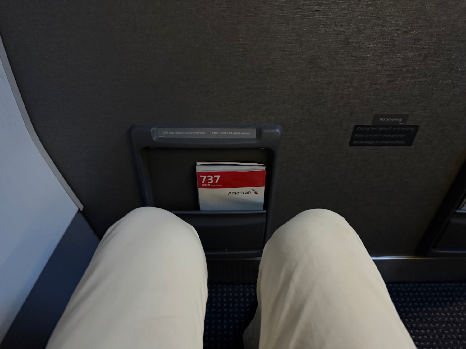 a person's legs in a seat with a ticket holder