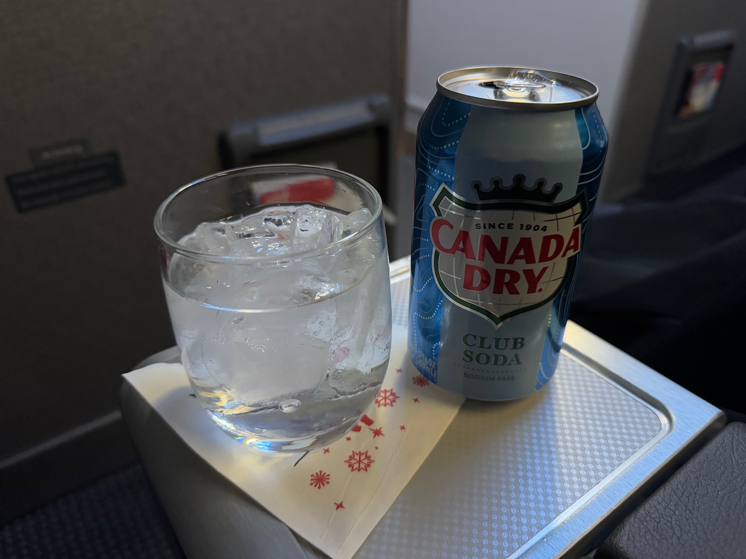 a can of soda and a glass of water on a tray