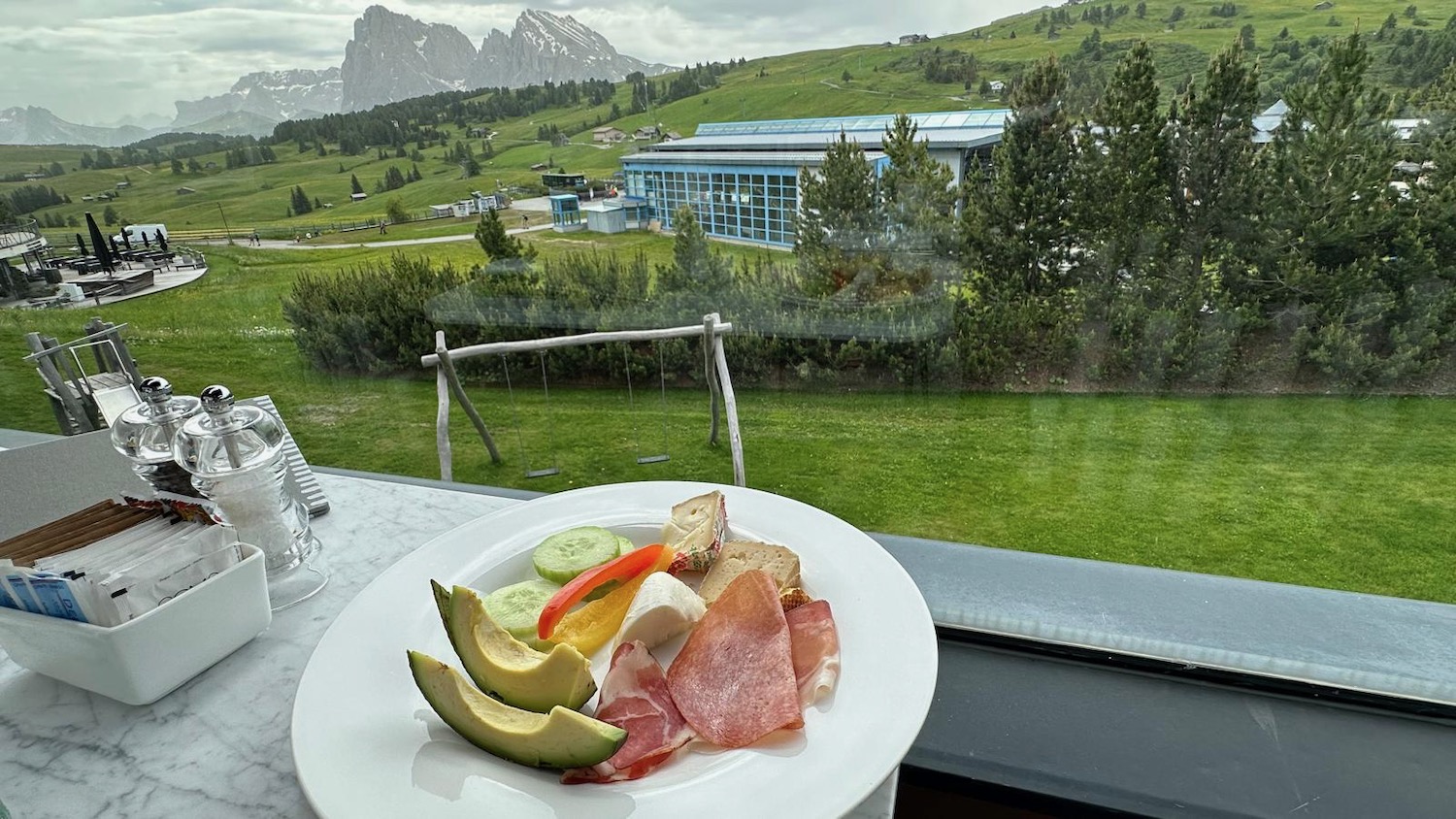 a plate of food on a table with a view of a mountain and a building