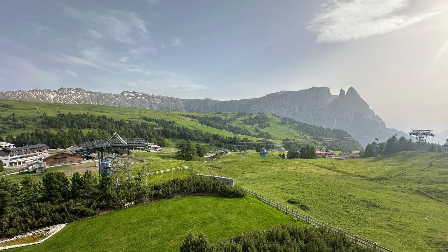 a green field with trees and mountains in the background