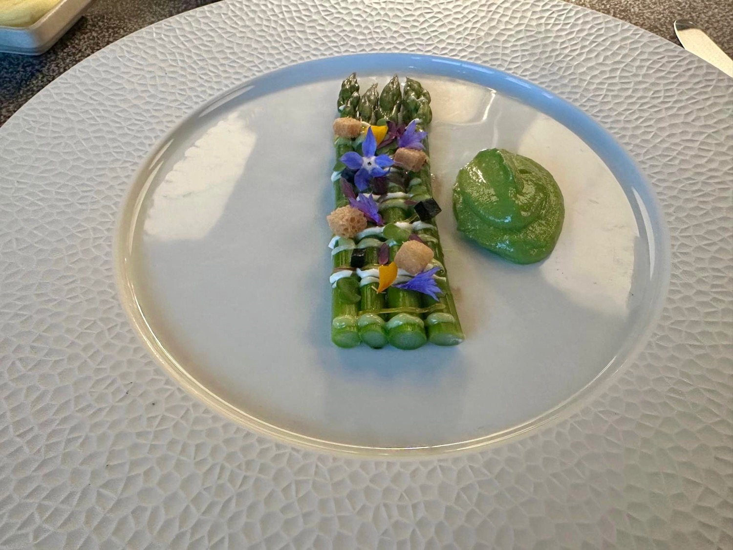 asparagus on a plate with flowers and a sauce on it