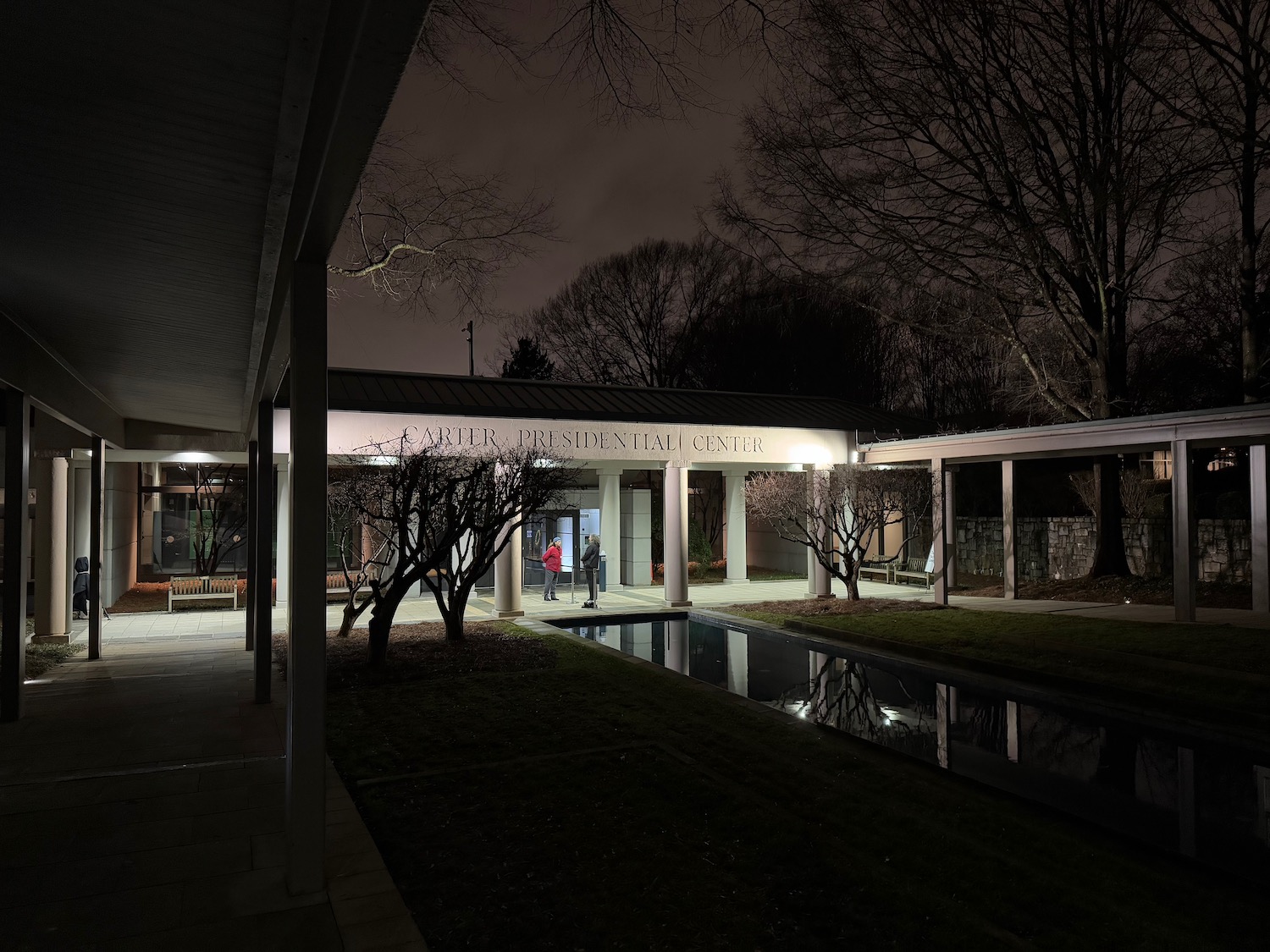 a building with a pool and trees at night