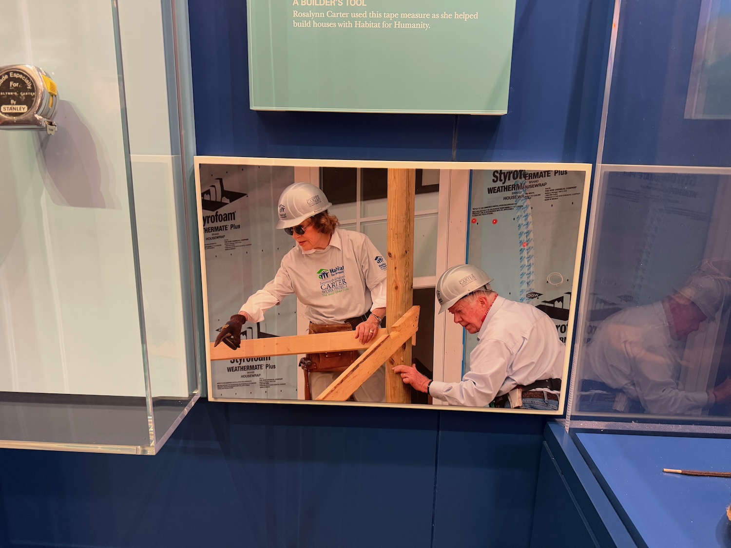 a picture of men wearing hardhats and working on a wood beam