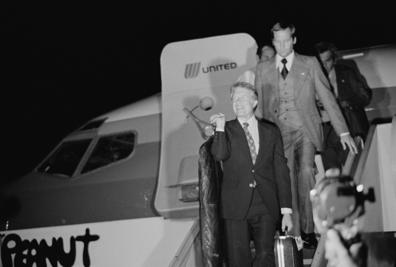 a man in a suit walking down a plane