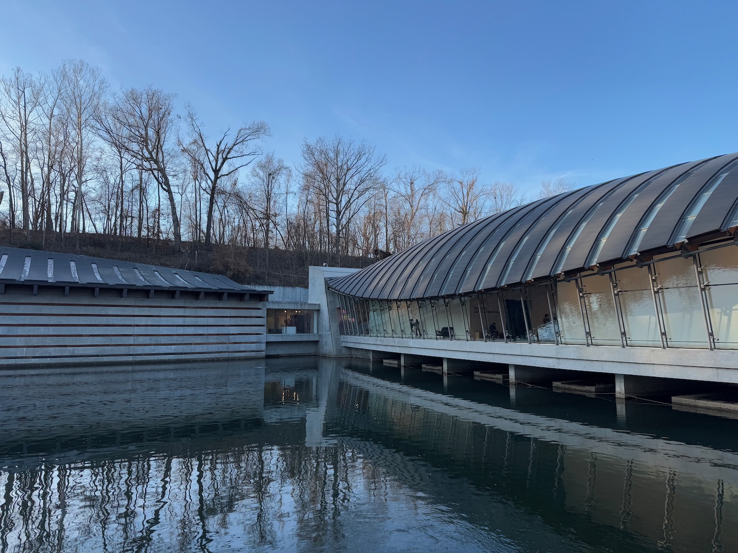 Crystal Bridges Museum of American Art with a curved roof and a body of water