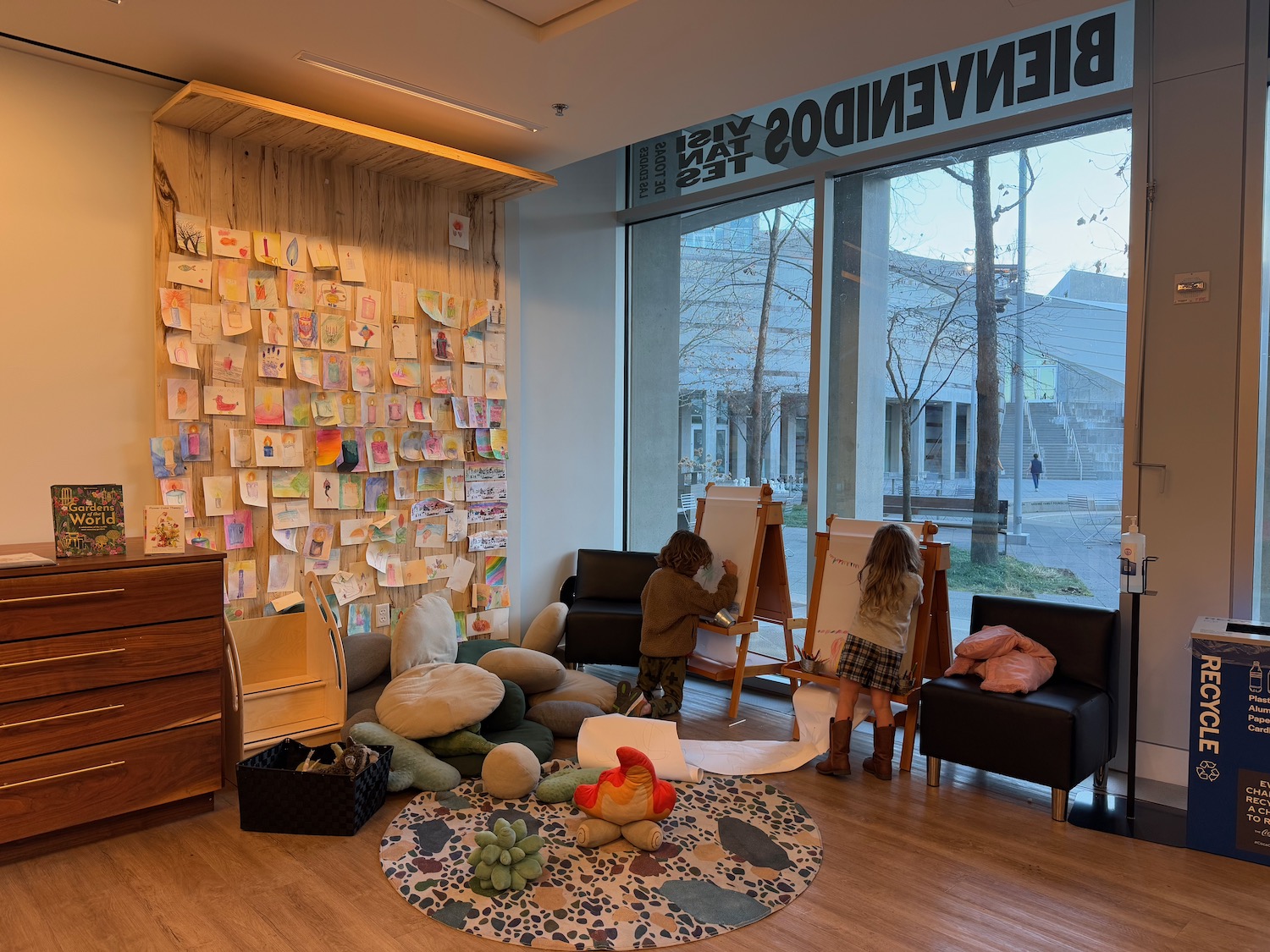 a room with a large window and a group of kids painting on a canvas