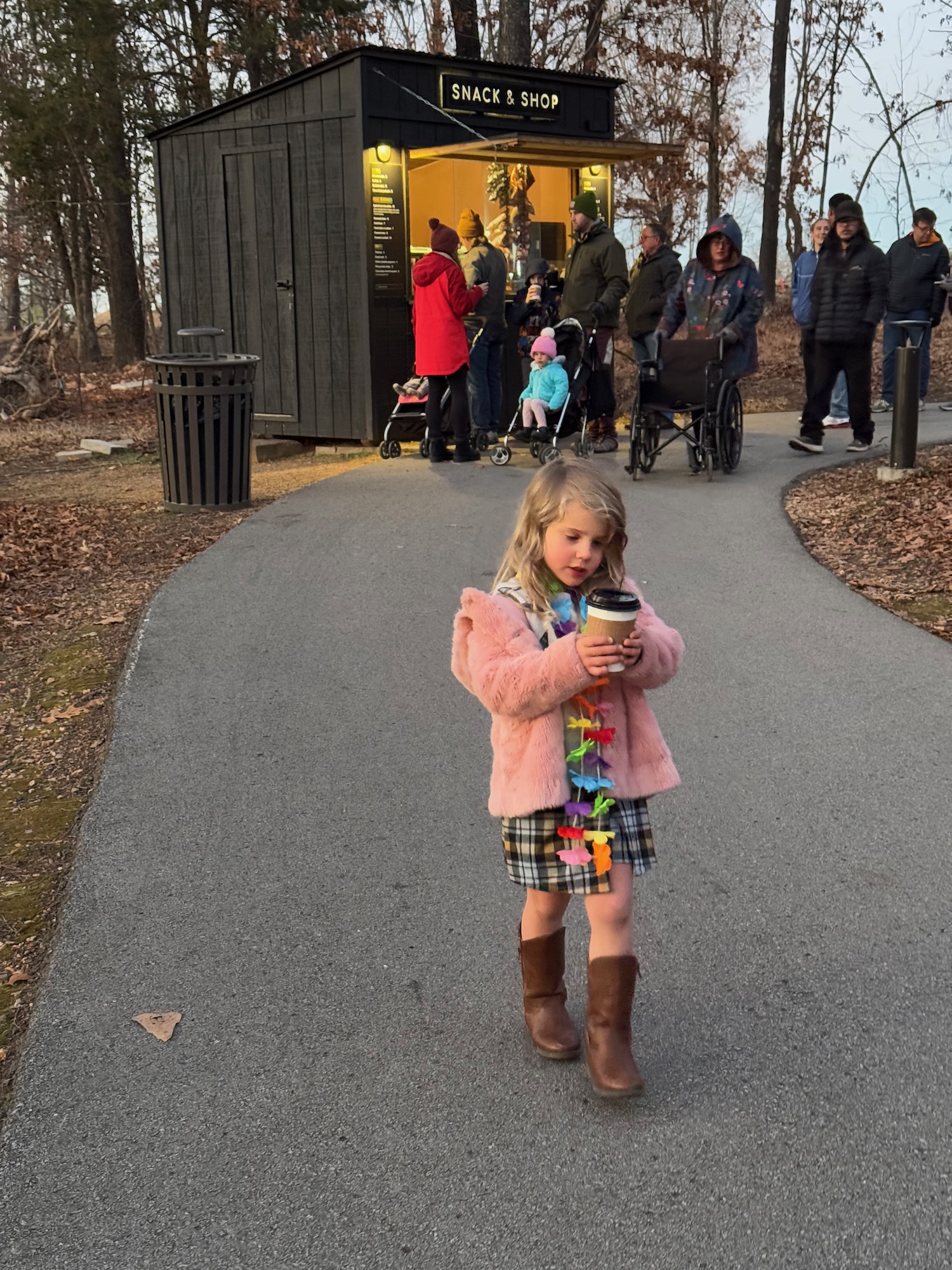 a girl holding a coffee cup and standing on a path