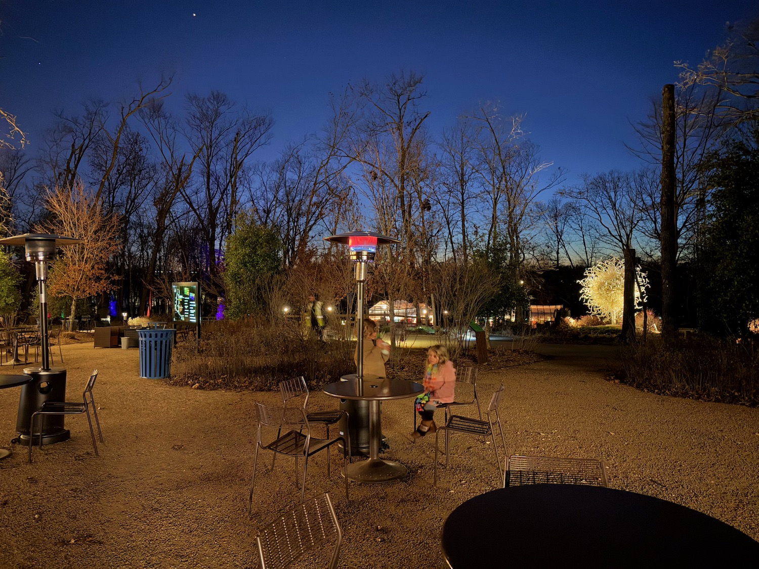 a group of people sitting at a table in a park