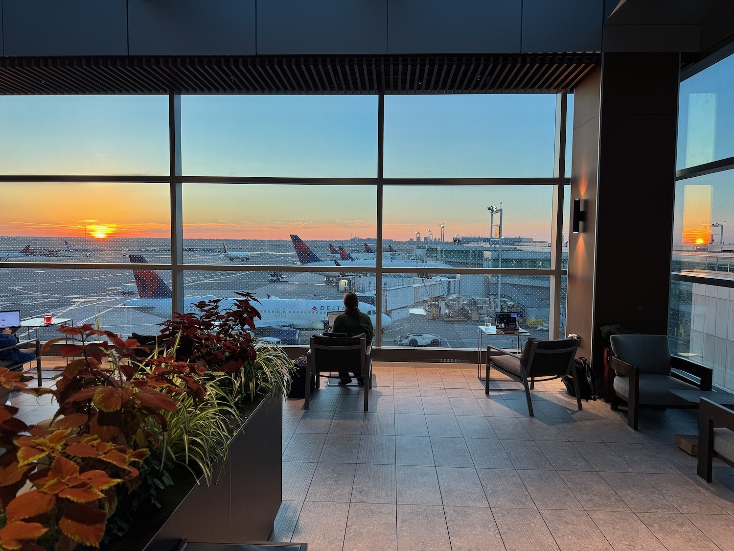 a person sitting in a chair looking out a window at an airport