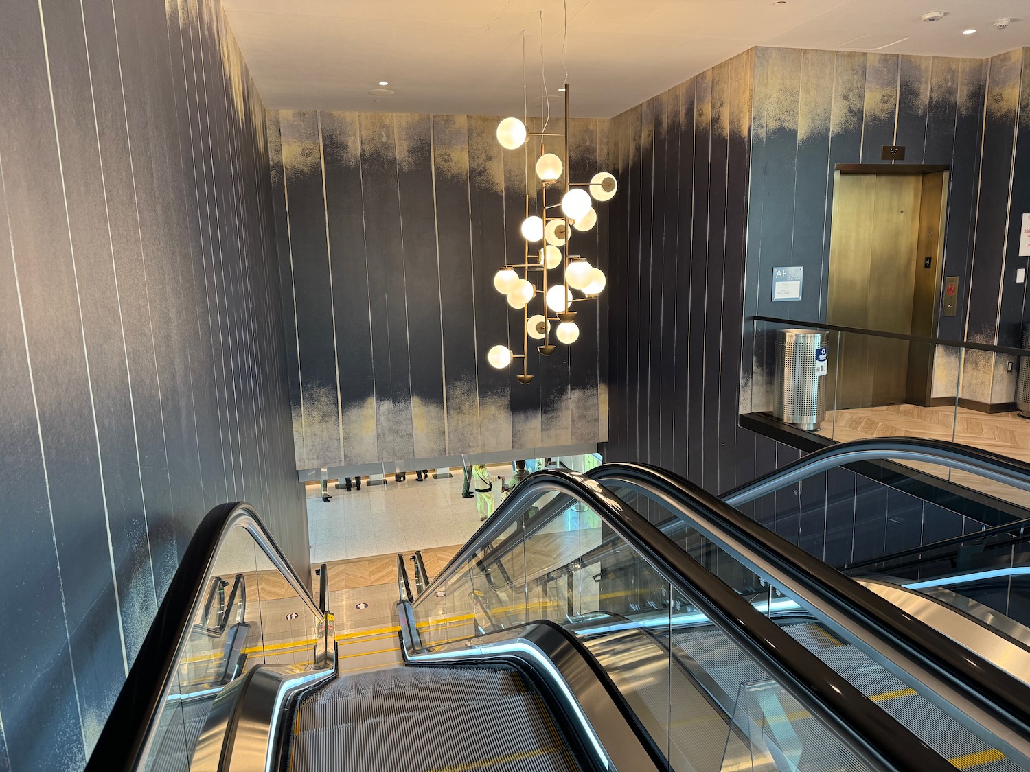 escalators in a building with a chandelier from the ceiling