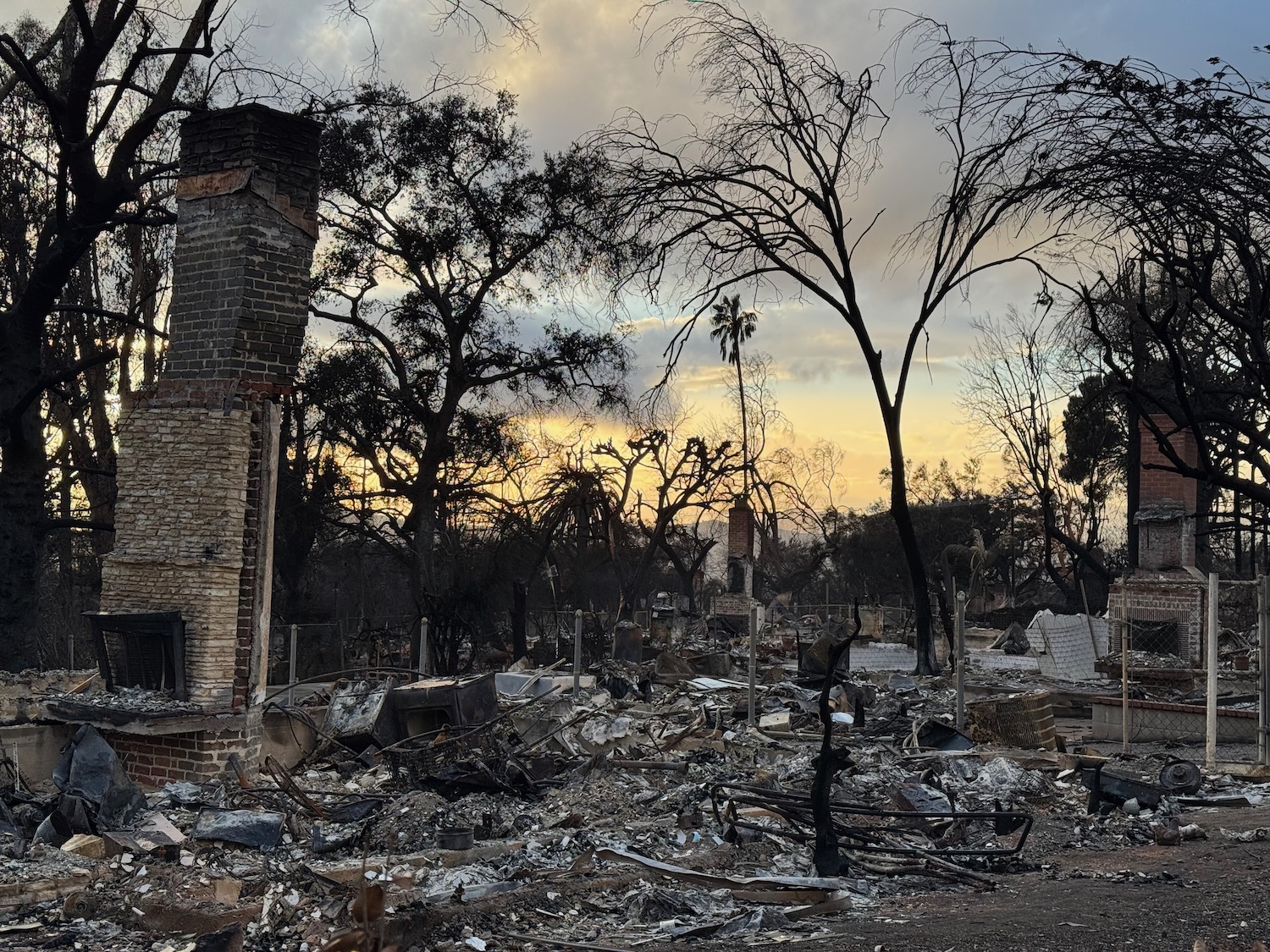 a burned down house with trees and a few smokestacks