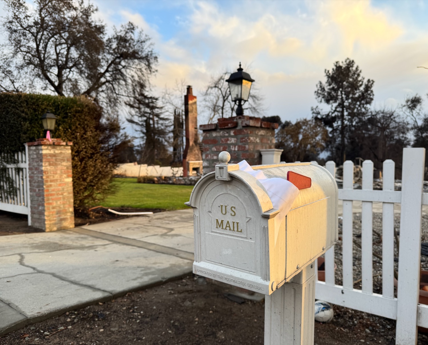 a white mailbox with a white fence and a white picket fence