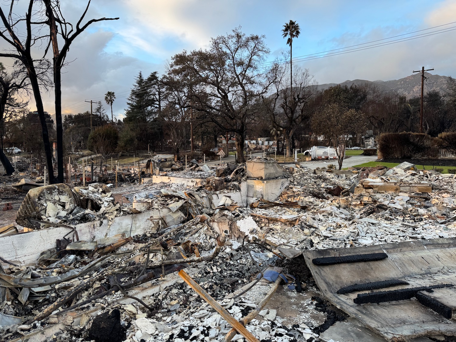 a destroyed house with trees and a hill in the background