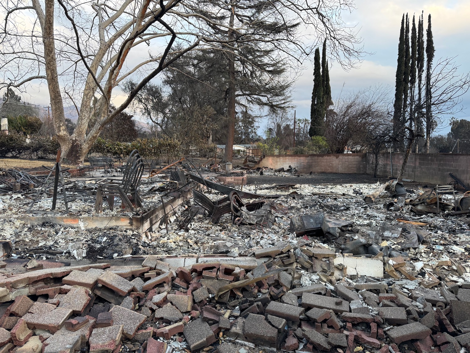 a destroyed house with debris and trees