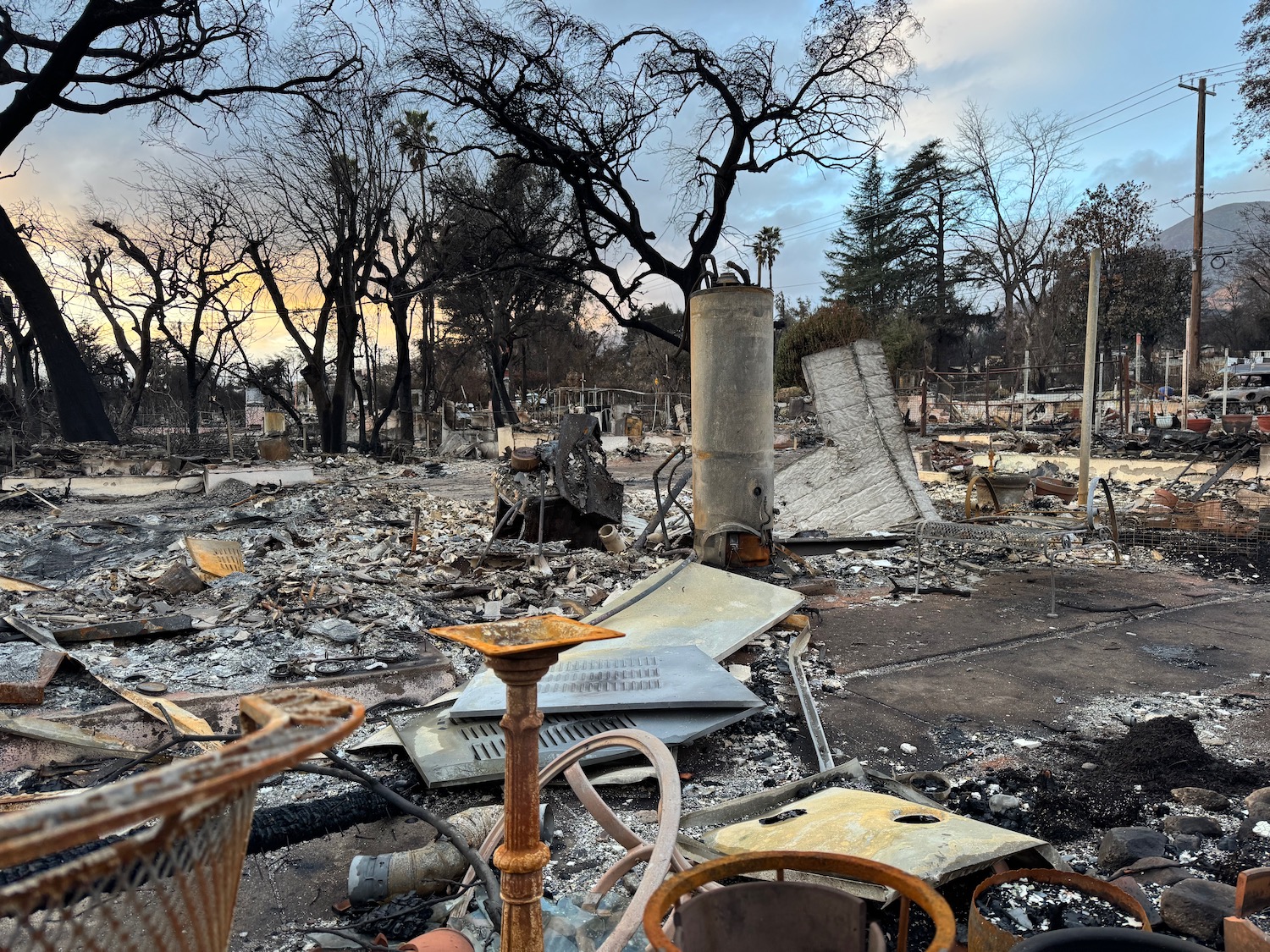 a burned out house with trees and a few debris