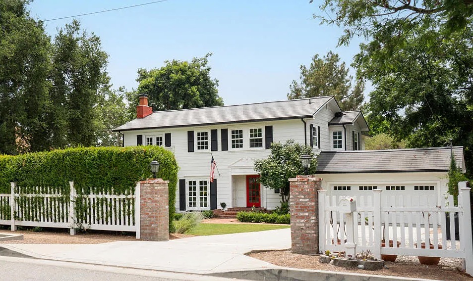 a house with a white fence and a red door