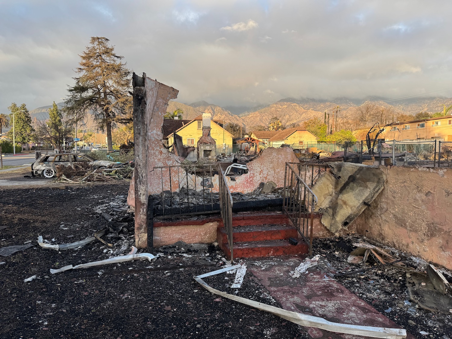 a destroyed house with a staircase and a mountain in the background