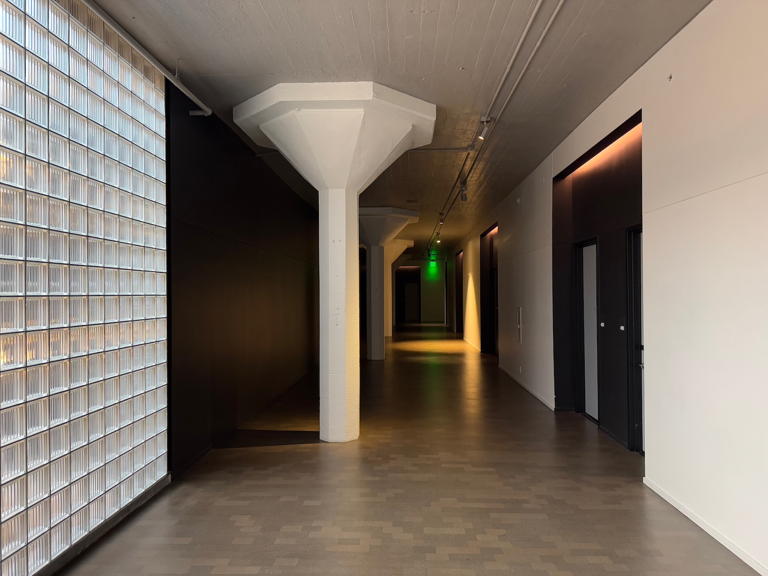 a hallway with a column and a green light