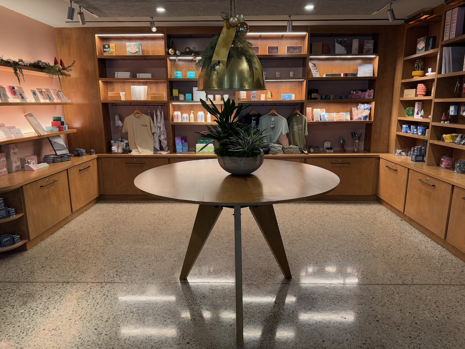 a room with a round table and shelves with clothing and a light fixture