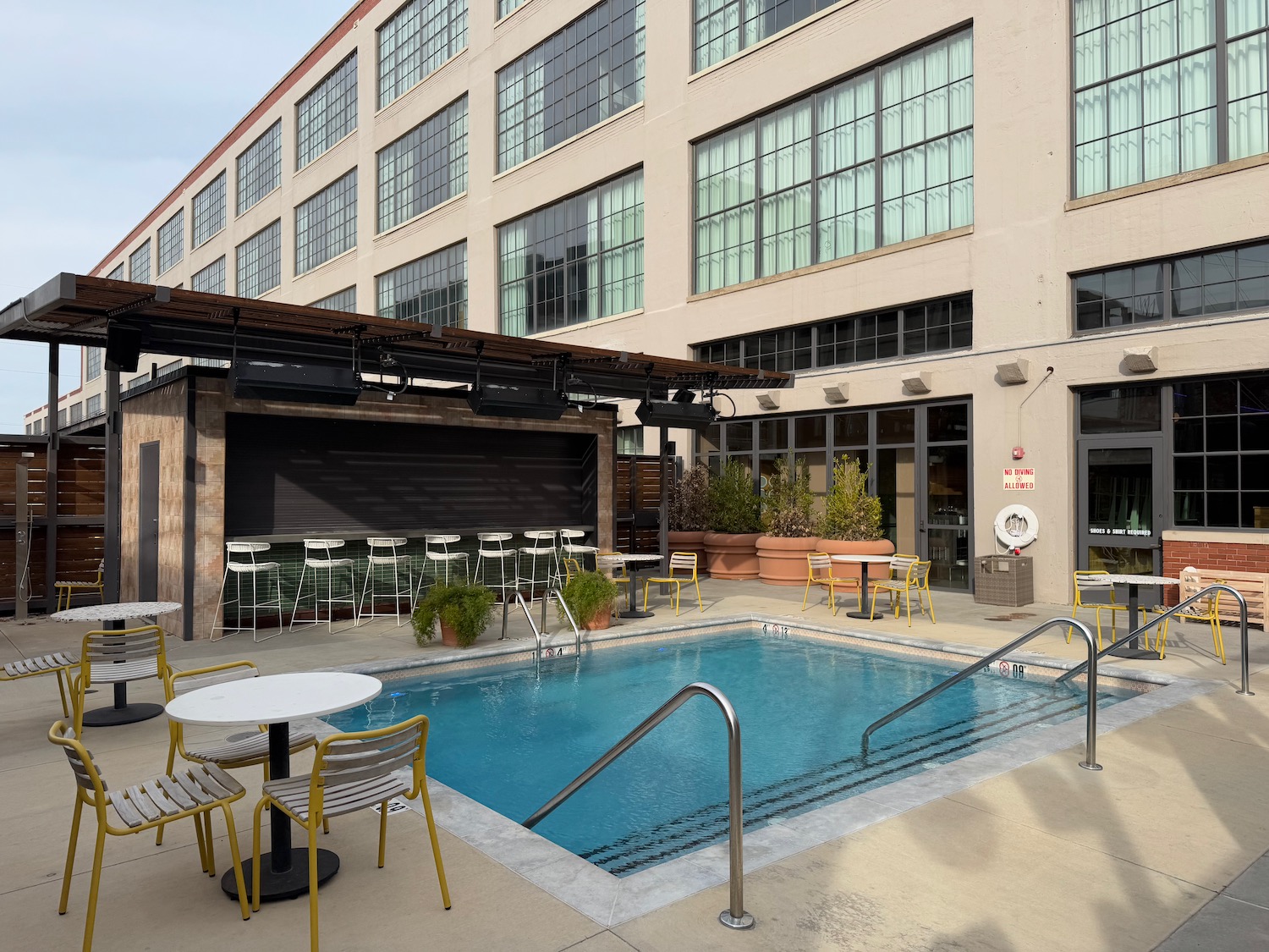 a pool with chairs and tables in front of a building