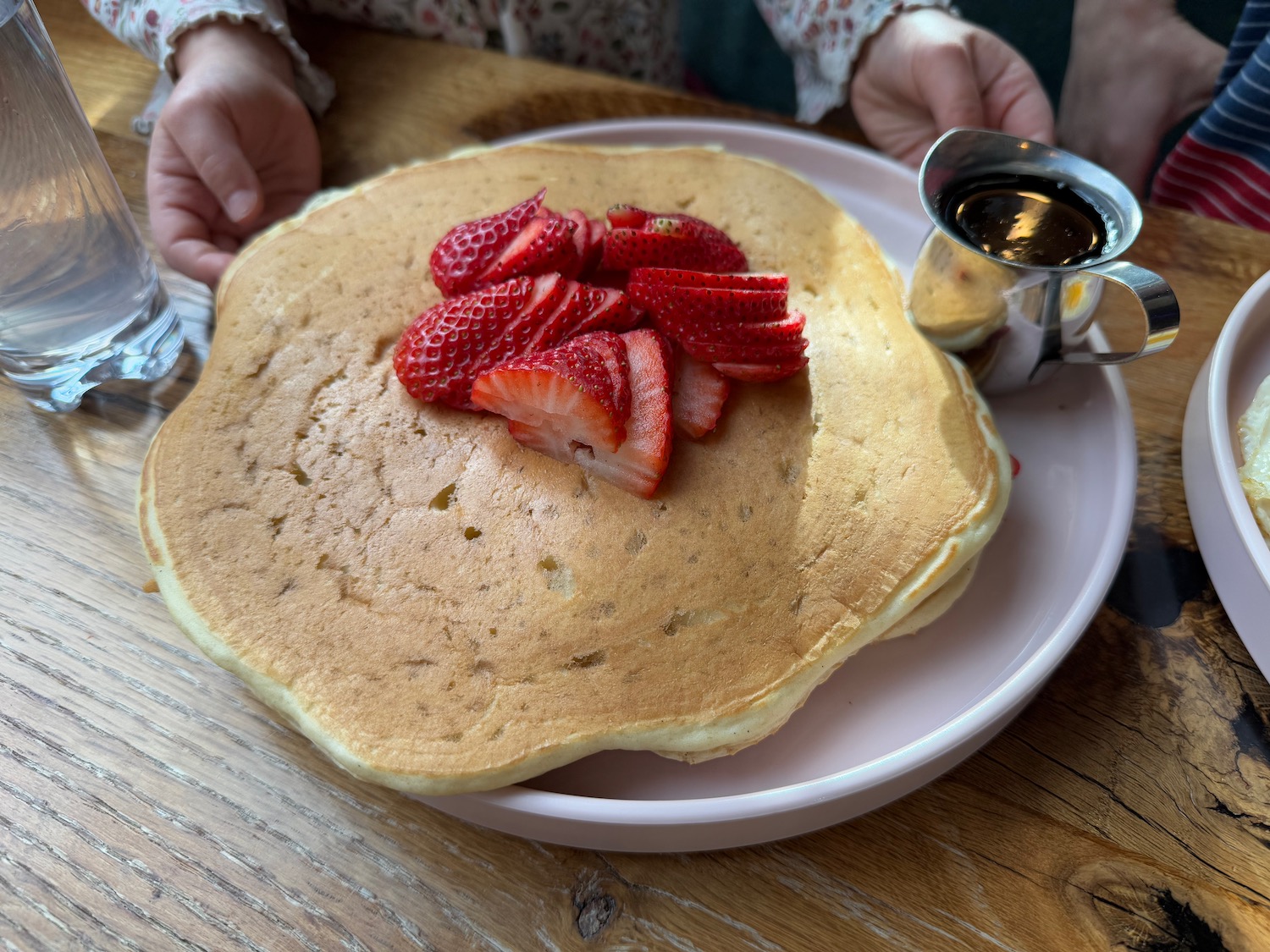 a plate of pancakes with strawberries and syrup