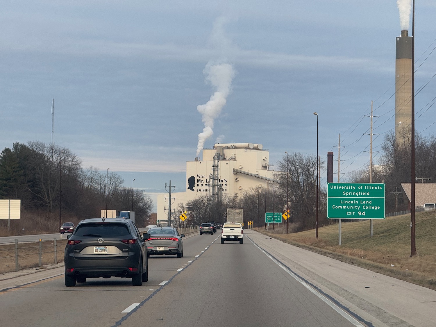 cars on the road with a factory in the background