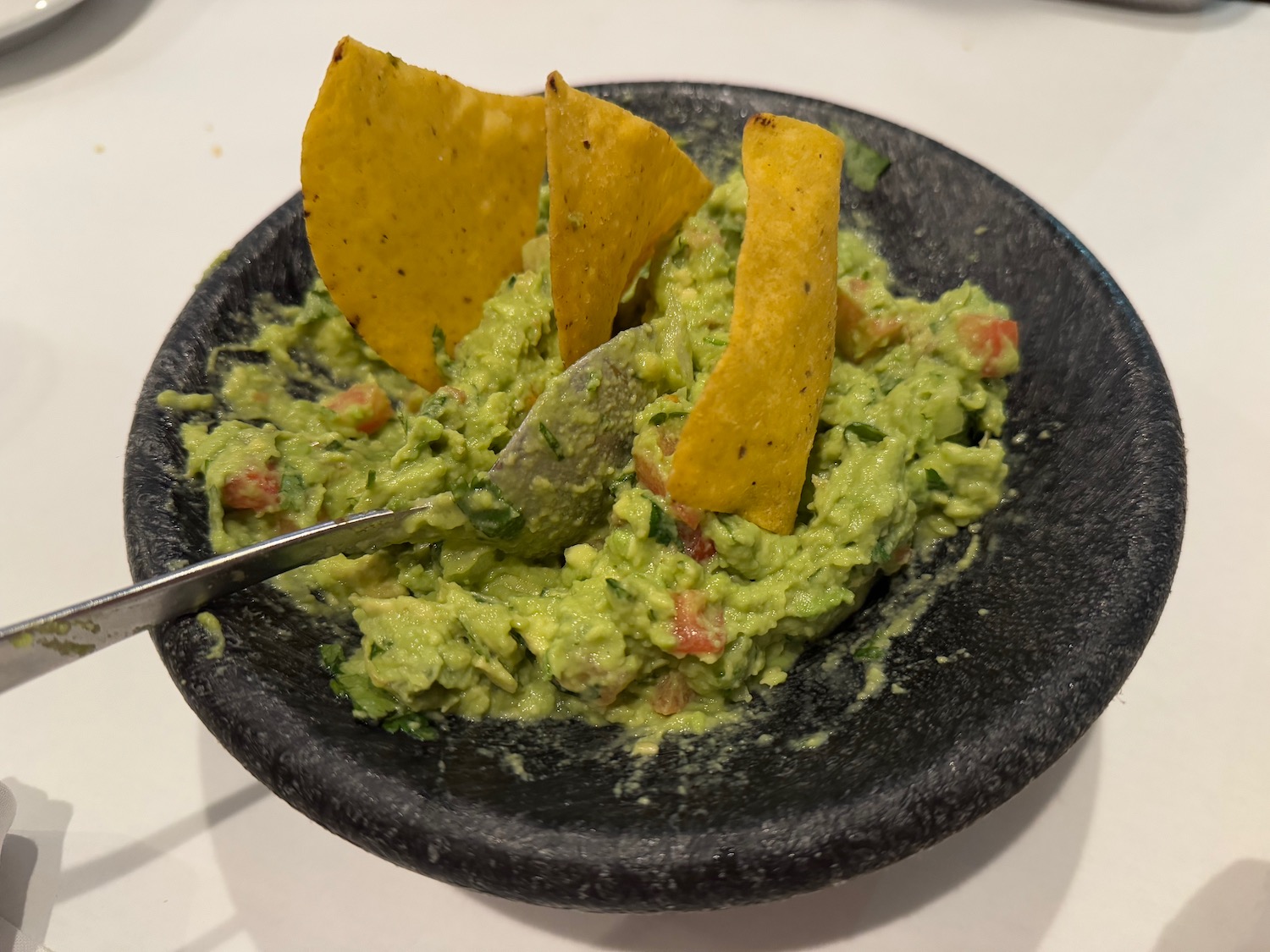 a bowl of guacamole with tortilla chips