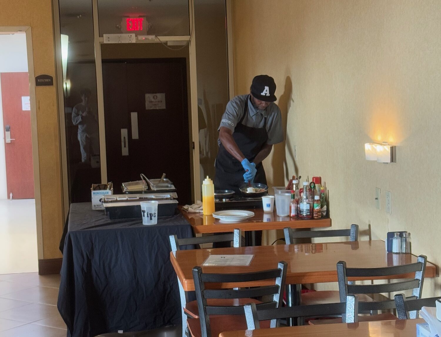 a man in a black hat and apron standing at a table