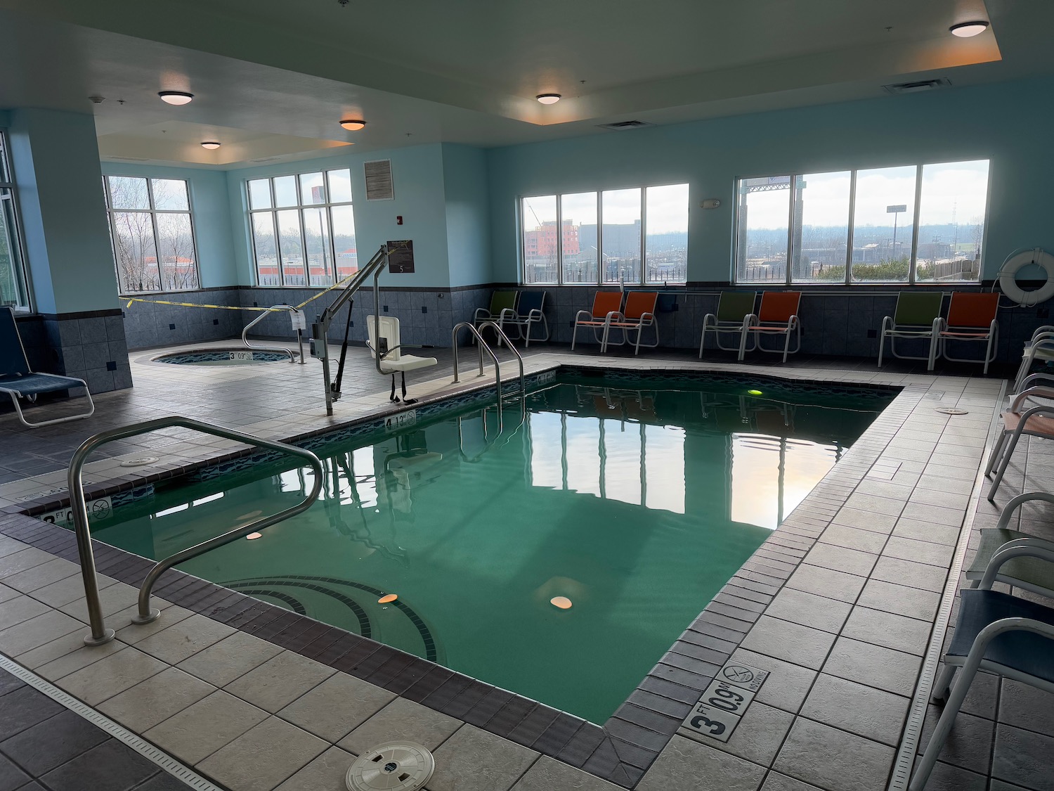 a indoor pool with chairs and a railing