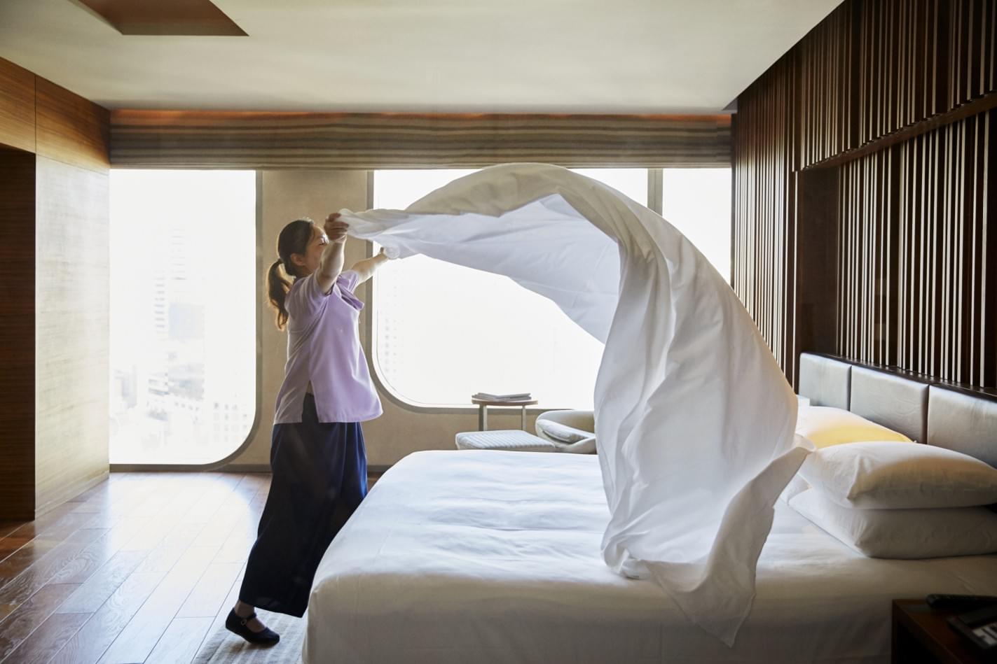 a woman holding a white sheet in a hotel room