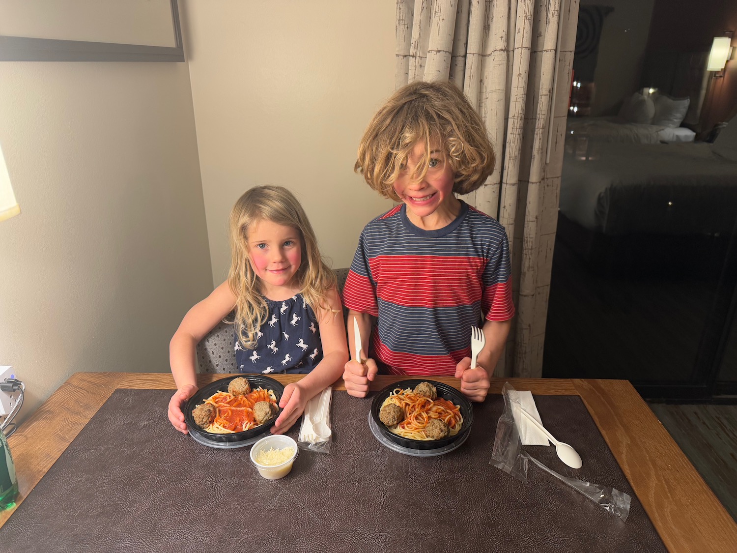 a boy and girl sitting at a table with plates of food