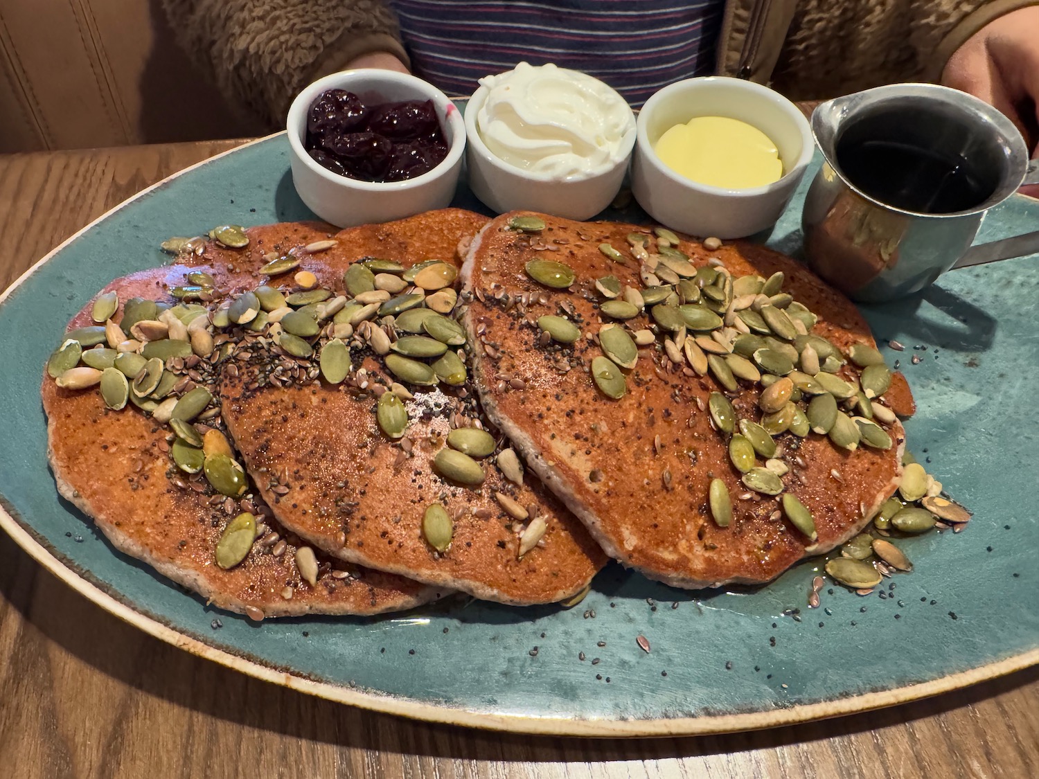 a plate of pancakes with toppings and three bowls of sauces