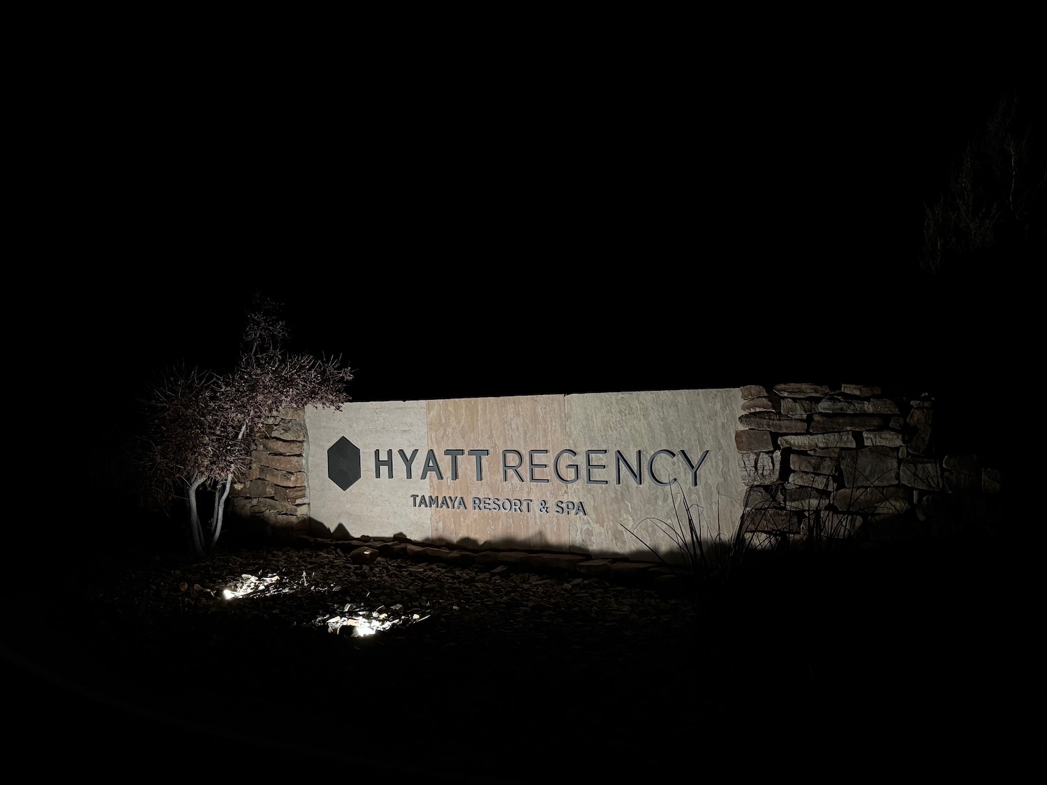 a sign at night with a stone wall