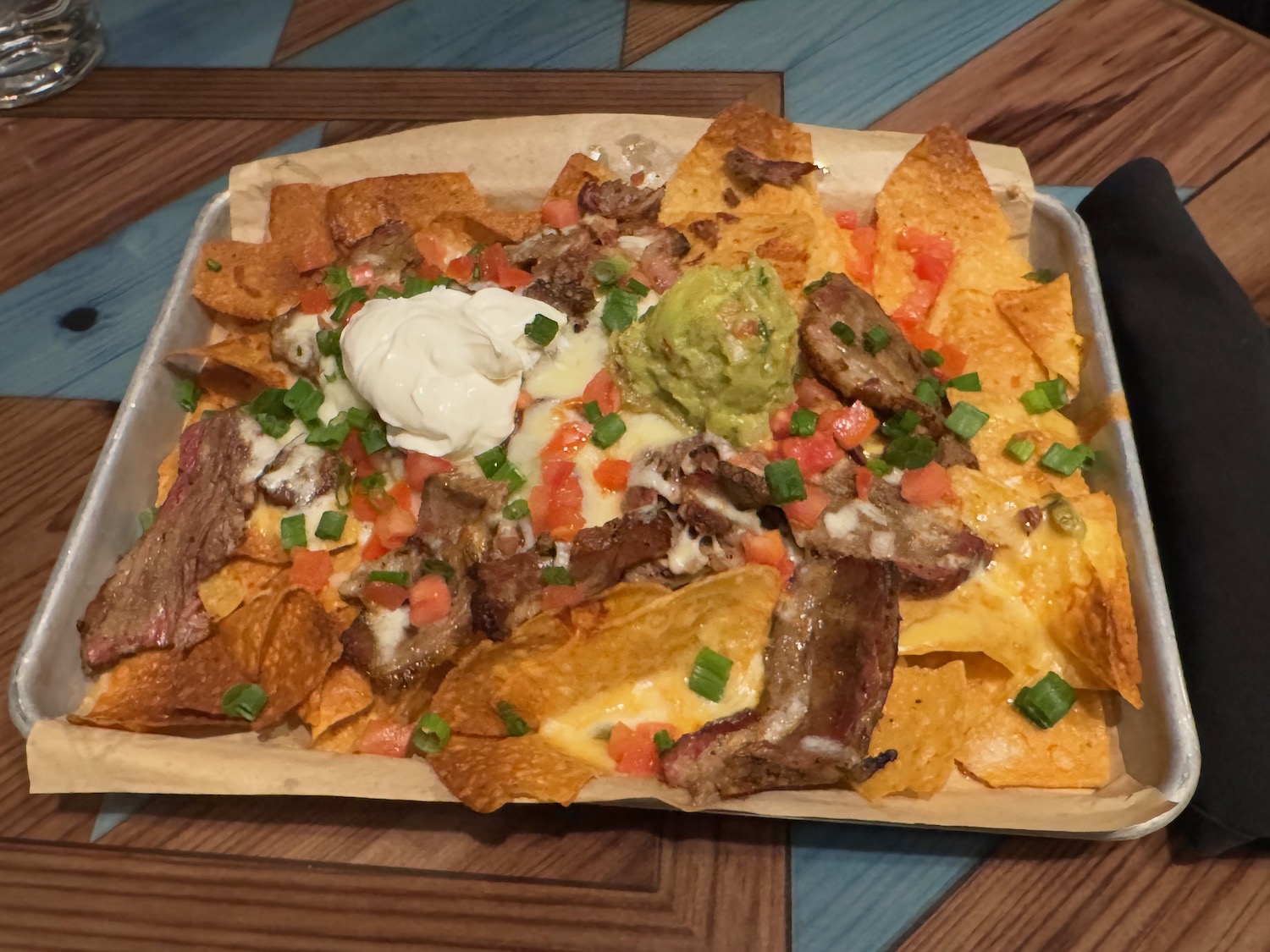 a tray of nachos with meat and cheese