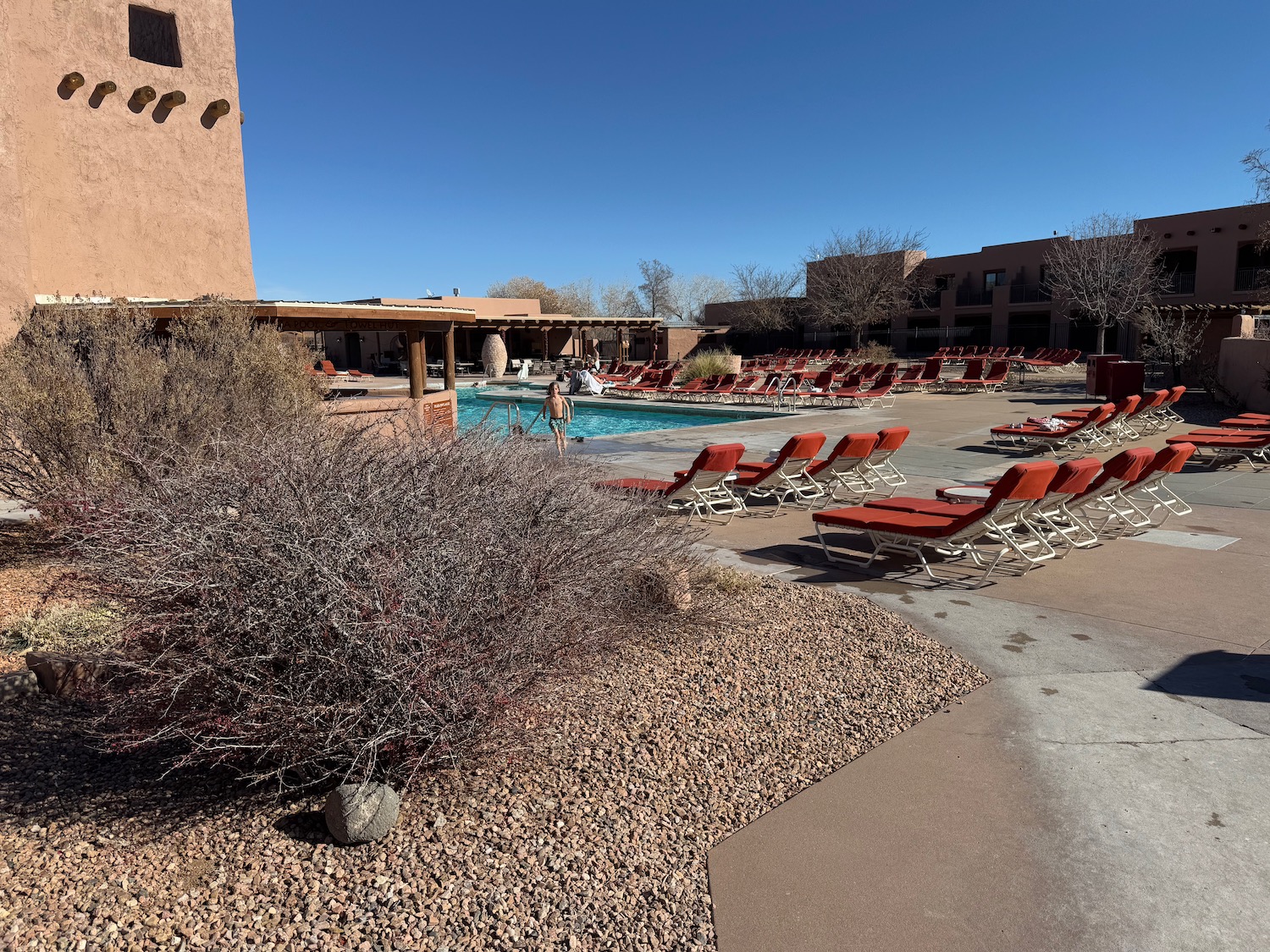 a pool with lounge chairs and a building