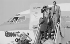 a man in a suit walking down a plane