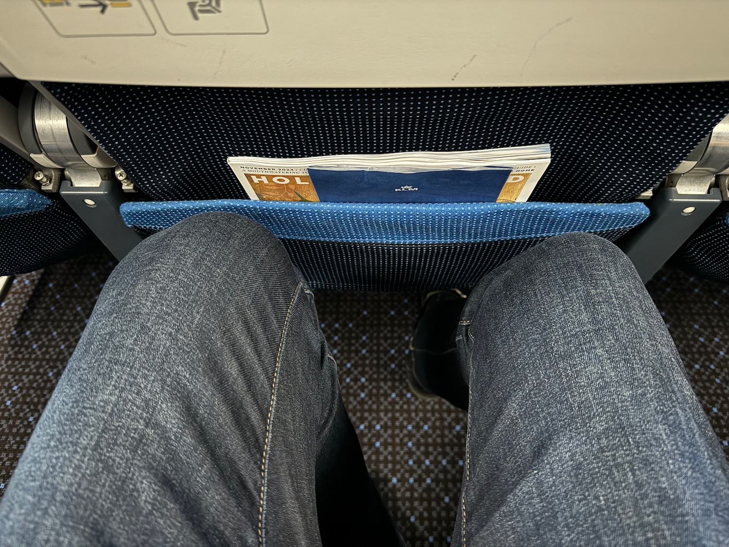 a person's legs in a seat with a pocket on the back