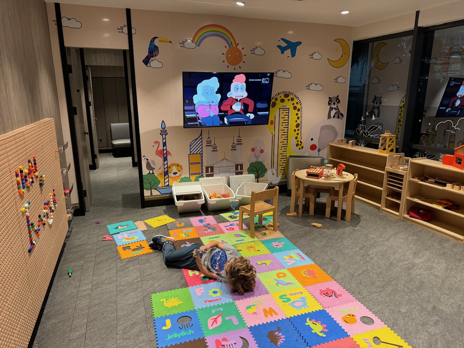 a child lying on a rug in a room with a tv