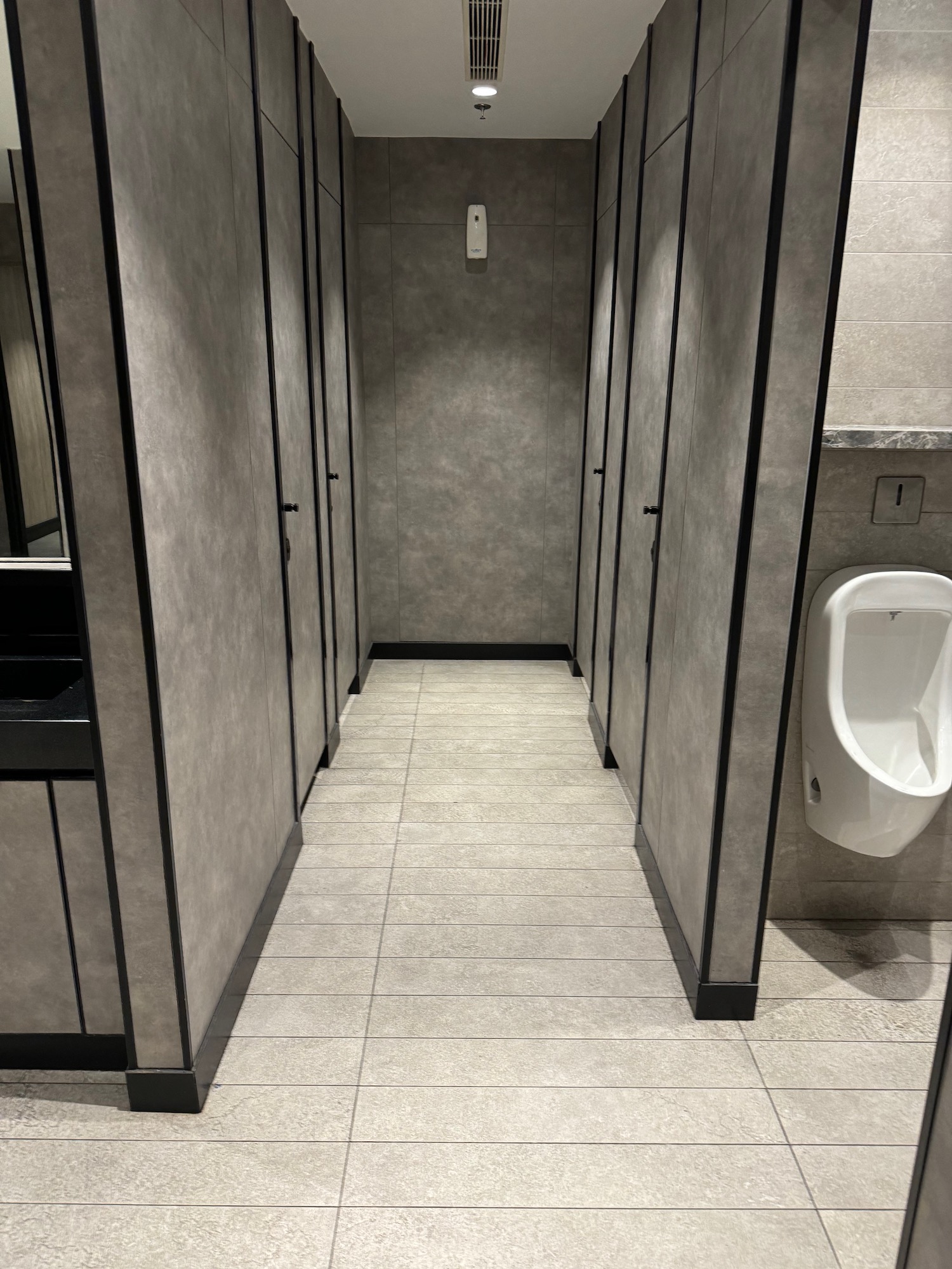 a bathroom with grey walls and a urinal