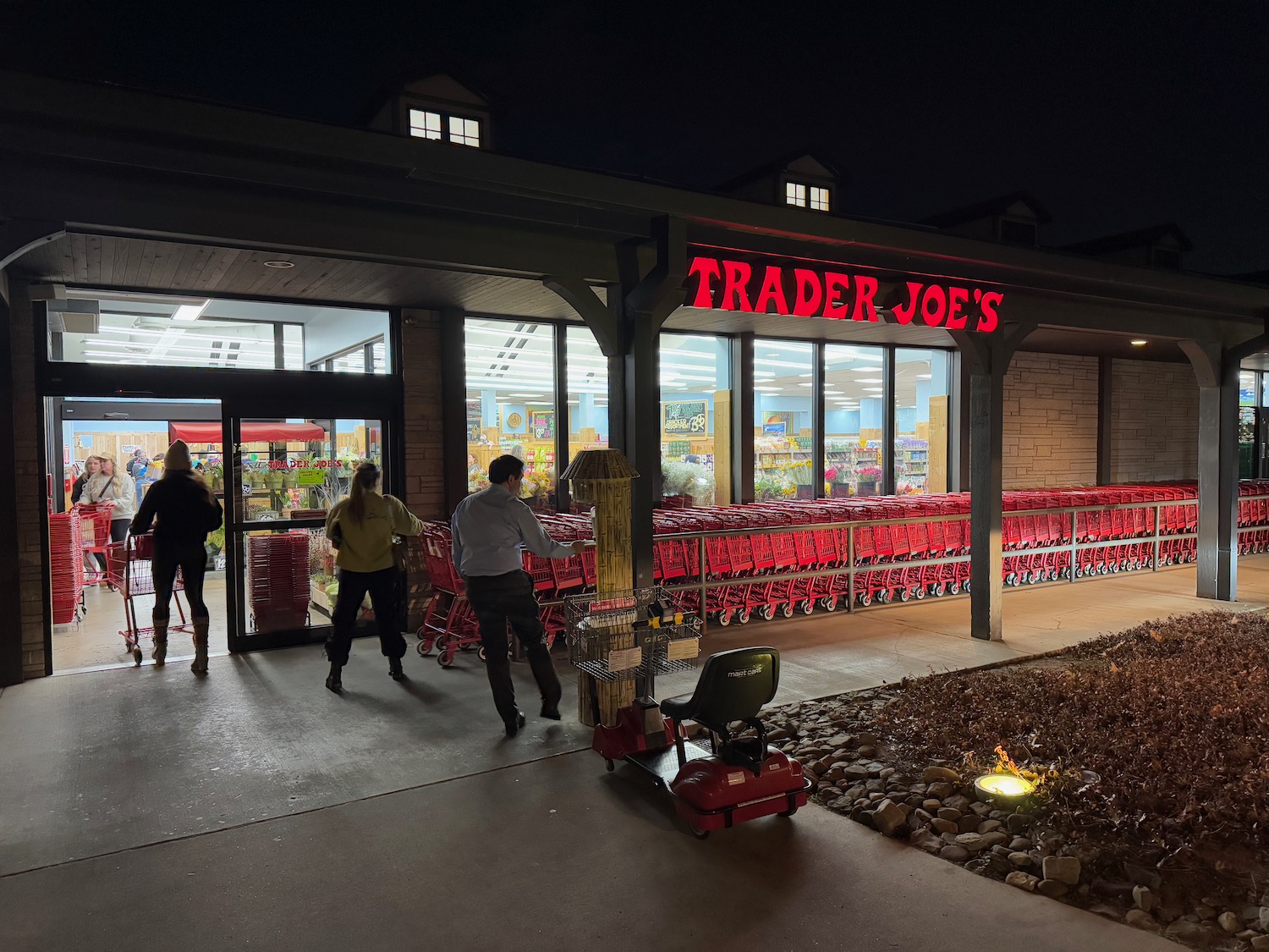 a store front with red shopping carts and people walking