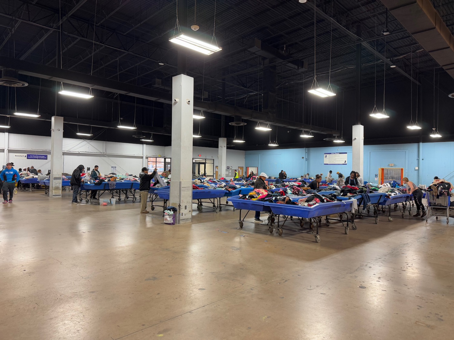 a large room with blue beds and people in it