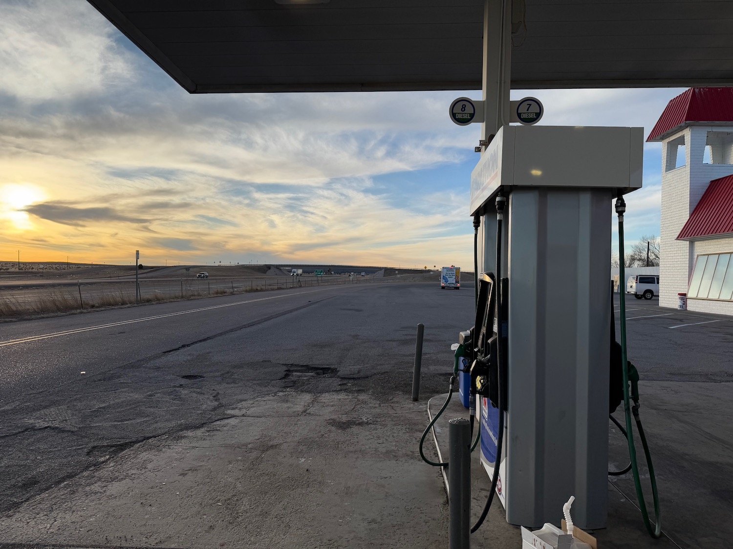 a gas station with a road and a cloudy sky