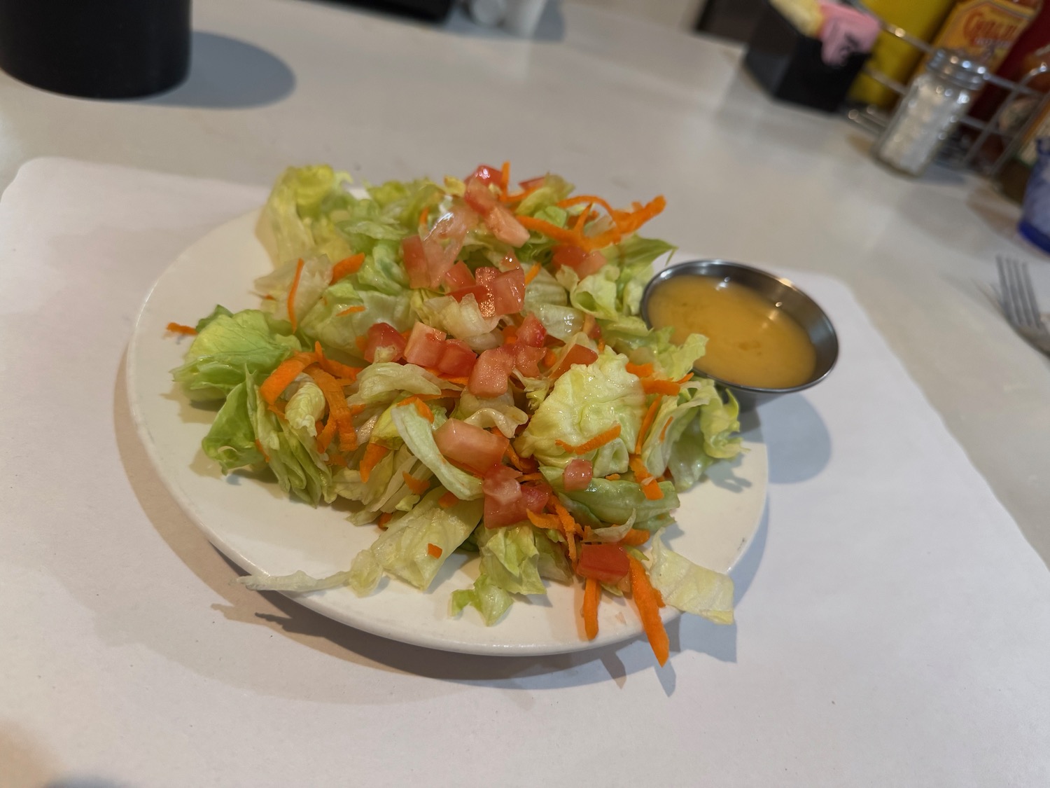 a plate of salad with a small bowl of sauce