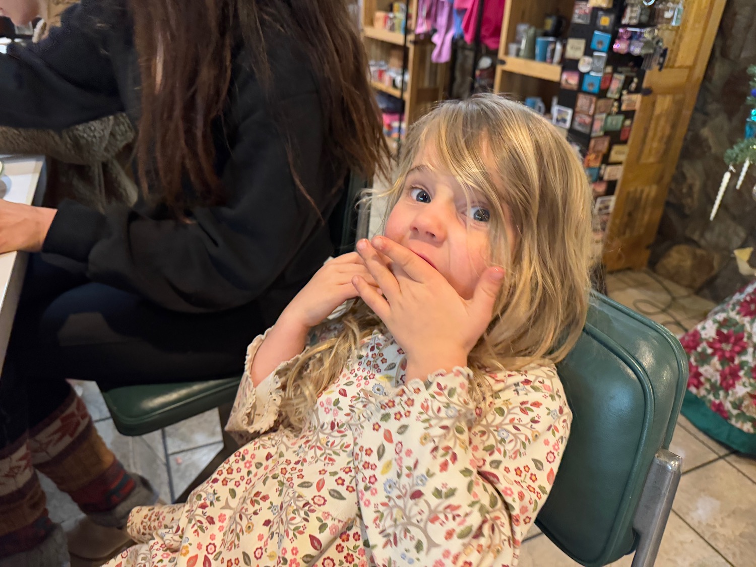 a girl sitting in a chair with her hand over her mouth