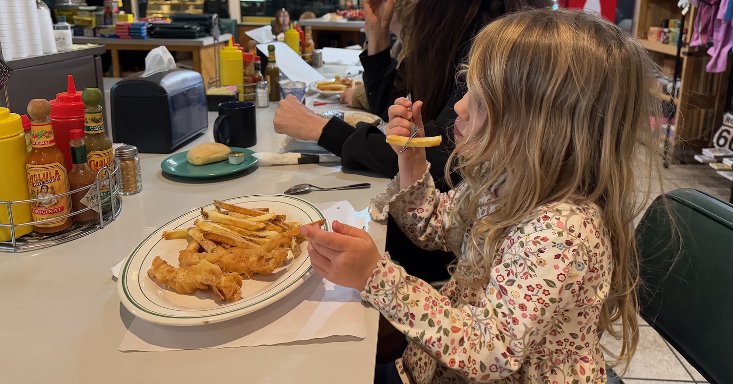 a girl eating french fries at a table