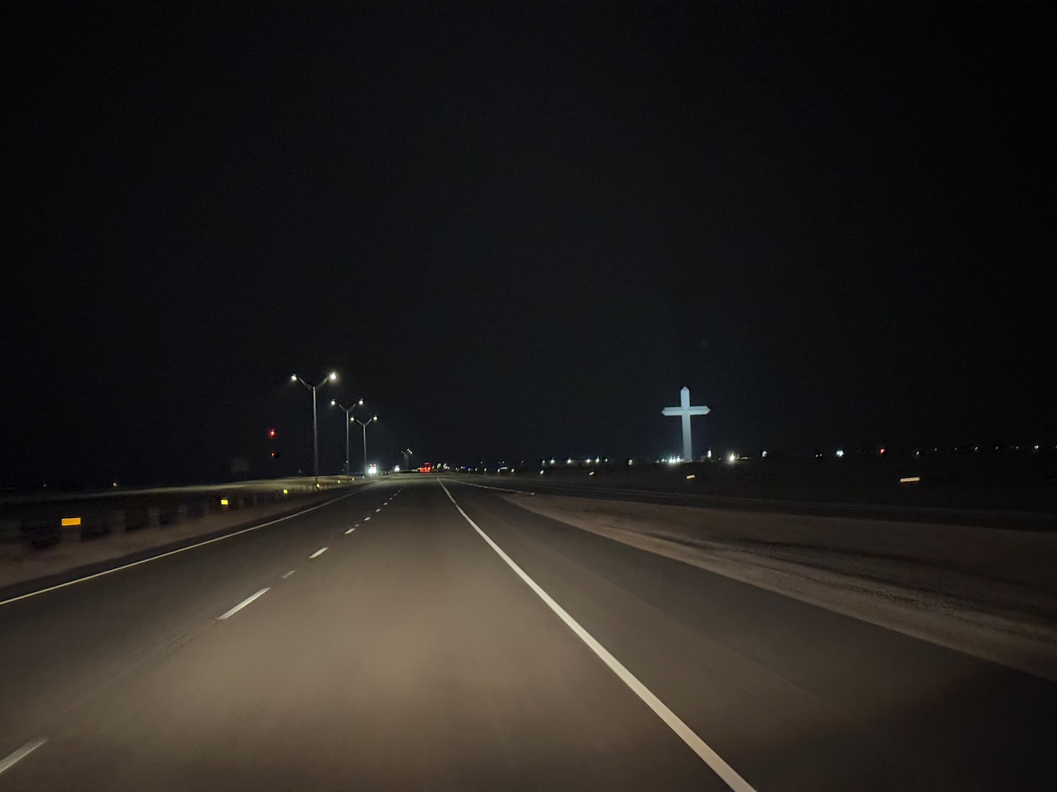 a road at night with a cross on the side