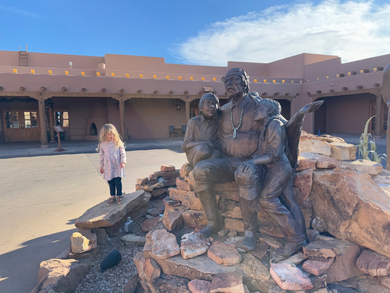 a girl standing in front of a statue of a man and a woman