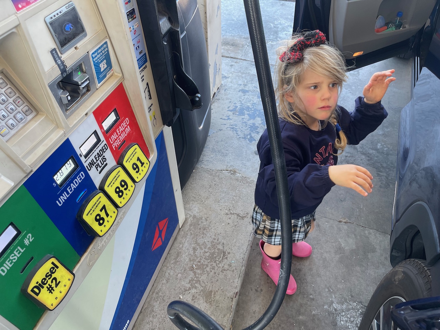 a girl standing next to a gas pump