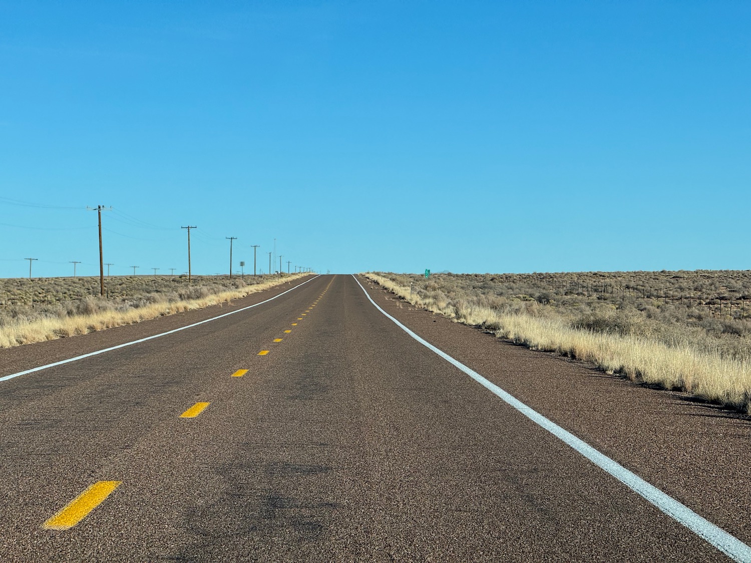 a road with yellow lines and a field of grass