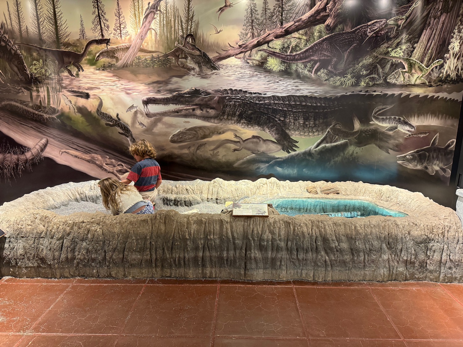 a child playing in a pool with a mural of dinosaurs